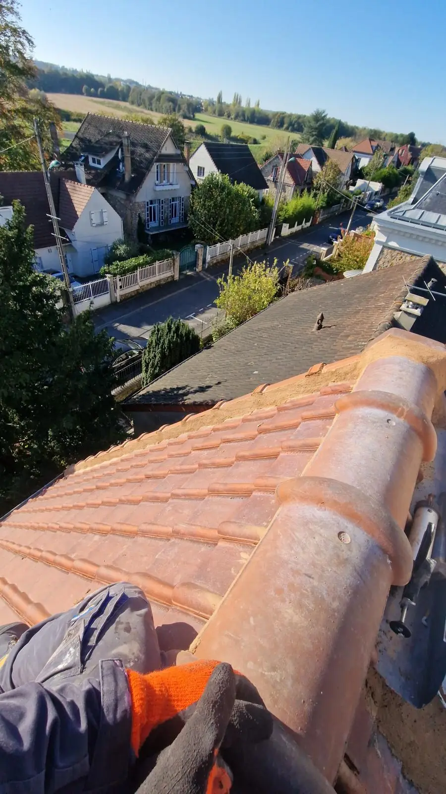 Faîtage en cours de rescellement au mortier, vue plongeante sur les maisons et la vallée